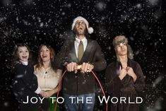 three people standing in front of a black background with the words joy to the world written on it