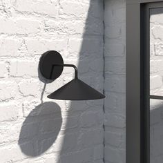 a white brick wall with a black lamp on it and a window in the background