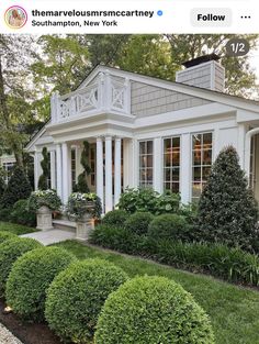 a house with white trim and windows surrounded by bushes in front of the house is featured on instagram