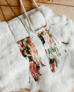 a white fur coat with fringes and beads hanging from it's side on a wooden floor