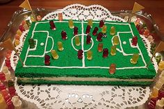 a cake that looks like a soccer field with gummy bears on it, sitting on top of a doily