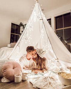 a man and woman are kissing in front of a teepee with lights on it