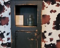 an old wooden cabinet with a glass bottle on top