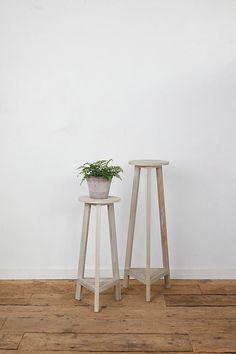 two small wooden stools with a plant on one side and a potted plant on the other