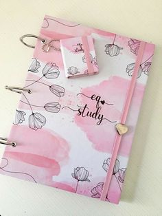 a pink and white notebook with writing on the cover that says eat study next to a pair of scissors