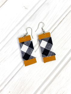 the earrings are made out of fabric and have black, white, and orange squares on them