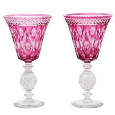 two pink glass goblets sitting next to each other on a white table top