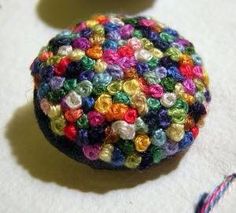 there is a small button made out of multicolored beads on the table top