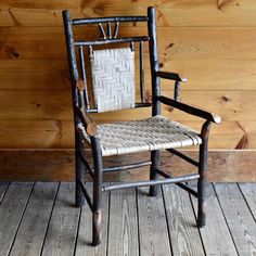 a wooden chair sitting on top of a wooden floor next to a wood paneled wall