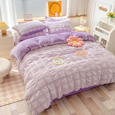 a bed with purple comforter and pillows on it