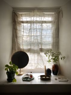 a window sill with plants and other items on it in front of a curtain