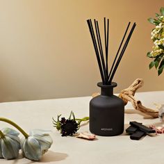 a black vase filled with reeds next to flowers and other items on a table