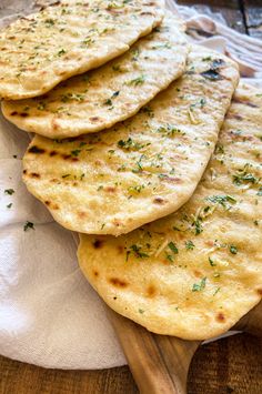 four flat breads sitting on top of a white cloth next to a wooden spoon