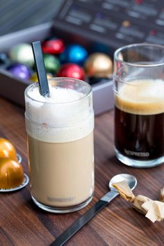 two drinks sitting on top of a wooden table next to spoons and christmas ornaments