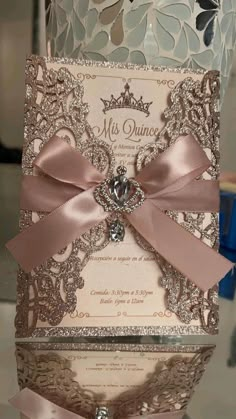 the wedding card is decorated with pink ribbon and a jeweled brooch on top