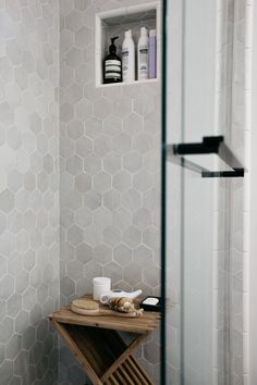 a bathroom with a stand up shower next to a shelf filled with personal care items