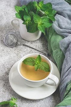 there is a cup of tea with mint on the saucer