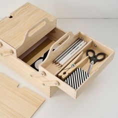 an open drawer with scissors, tape and other items in it on a white surface