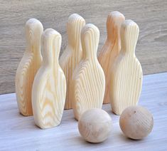 four wooden bowling pins and three balls on a table