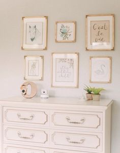 a white dresser with pictures on the wall above it