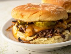 two cheeseburgers with pickles and onions in a white bowl