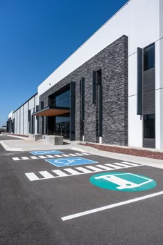 an empty parking lot in front of a large building with signs painted on the ground