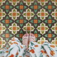 a person standing in front of a wall with colorful tiles on it and their feet propped up