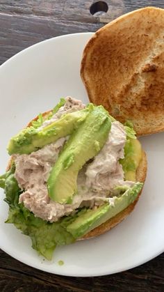 there is a sandwich with lettuce and tuna on it next to a piece of bread