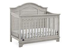 a baby crib with white bedding and wood trimmings on the sides