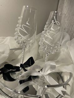 two wine glasses sitting on top of a metal tray with ribbons and bows around them