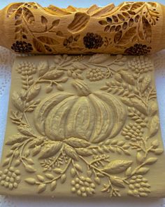 a carved pumpkin and vine design on parchment paper next to a rolled up scroll roll