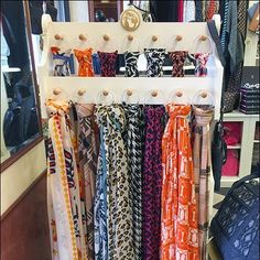 an assortment of scarves hanging on a rack