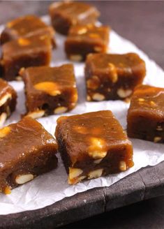 several pieces of brownie sitting on top of a piece of wax paper with nuts