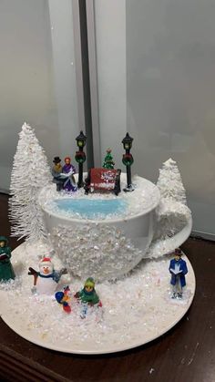 a christmas cake is decorated with snow and small figurines