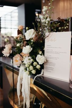 a menu sitting on top of a black counter next to flowers and an empty card