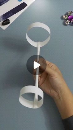 a hand holding a piece of paper with circles on it and an object in the background