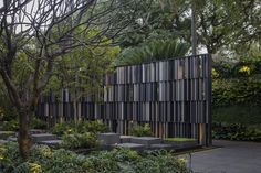 an outdoor garden with trees, plants and concrete blocks on the side of the building