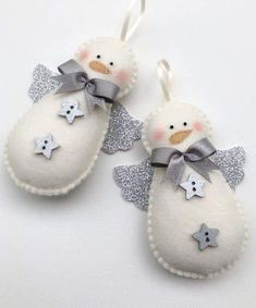 two white snowmen with silver bows and stars on them are hanging from the strings