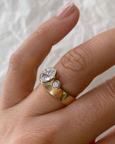 a woman's hand with a gold and diamond ring on top of her finger