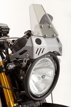 a close up of a motorcycle headlight on a white background with a black handlebar