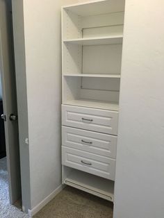 an empty closet with white drawers and shelves