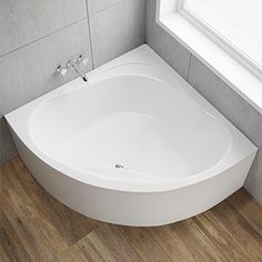 a white bath tub sitting on top of a wooden floor next to a window in a bathroom