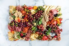 a platter filled with lots of different types of cheese and meats on top of a marble table