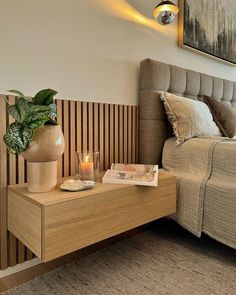 a bed room with a neatly made bed and a plant on the end table next to it