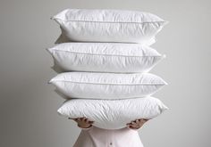 a person holding four pillows in front of their face