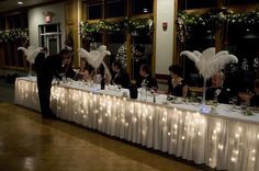 people sitting at tables with white table cloths and angel decorations on the wall behind them