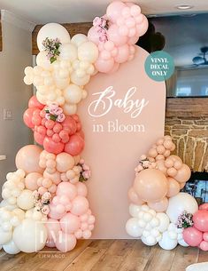 a baby in bloom balloon arch with flowers and balloons on the wall for a baby shower