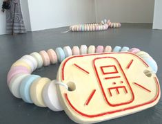 a woman standing in an art gallery looking at artwork on the floor with colorful beads around her