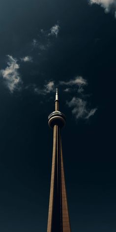 a tall tower with a clock on it's side under a cloudy blue sky