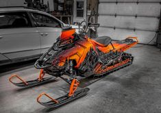 an orange and black snowmobile parked in a garage